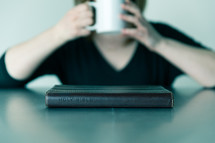 man drinking hot cocoa and a Bible on a table 