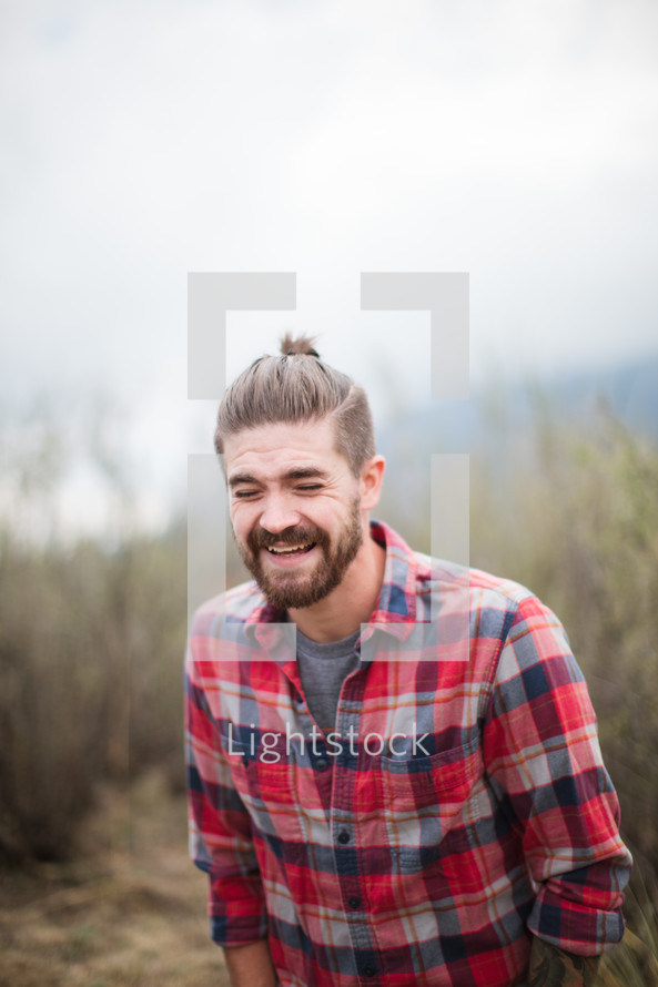 man in a plaid shirt laughing 