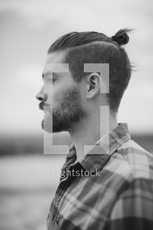 side profile of a bearded man in a plaid shirt 