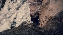 Water running down mountain rocks into a waterfall.