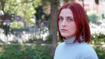 Red haired woman looks into the camera with a serious look. 