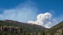 smoke from a wildfire coming from behind a mountain 