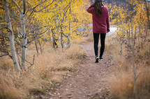 a woman walking on a path to a lake in fall 