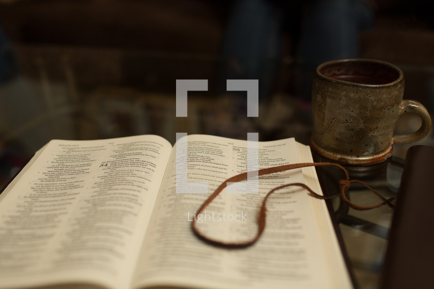 coffee cup in front of an opened Bible 