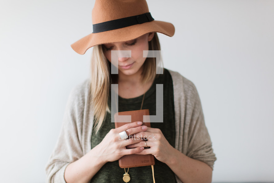 a woman in a hat holding a Bible 