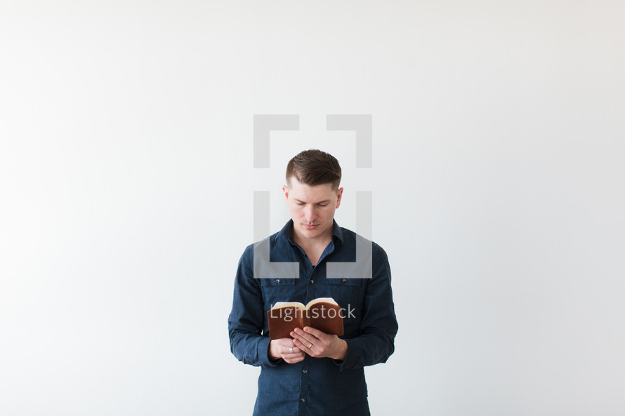 man standing reading a Bible 