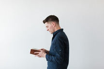 man standing reading a Bible 