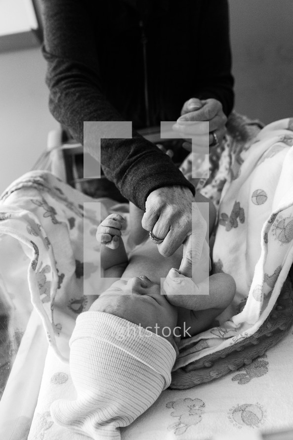 a newborn baby holding onto grandmother's finger 
