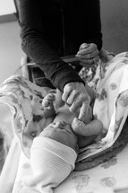 a newborn baby holding onto grandmother's finger 