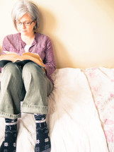 a woman reading a Bible on a bed 