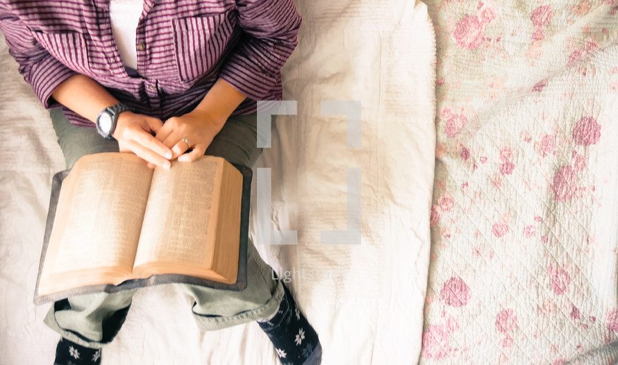 a woman reading a Bible in bed 