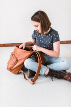 teen girl looking in a purse 