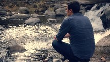 Man sitting outside by a waterfall appreciating the beauty of nature.