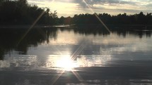 Timelapse of the sun setting over a lake with shimmering water.