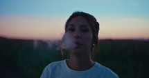 Woman vaping outside during sunset