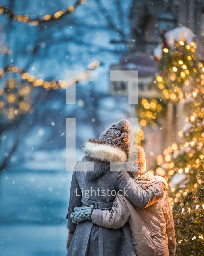 siblings hugging in winter snow 