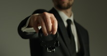 Business man holding handcuffs in front of camera - close up on handcuffs