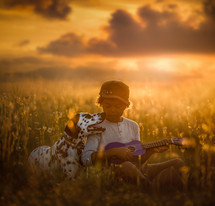 a boy sitting in a field next to his dog 