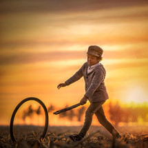 a chid playing with a stick and tire 