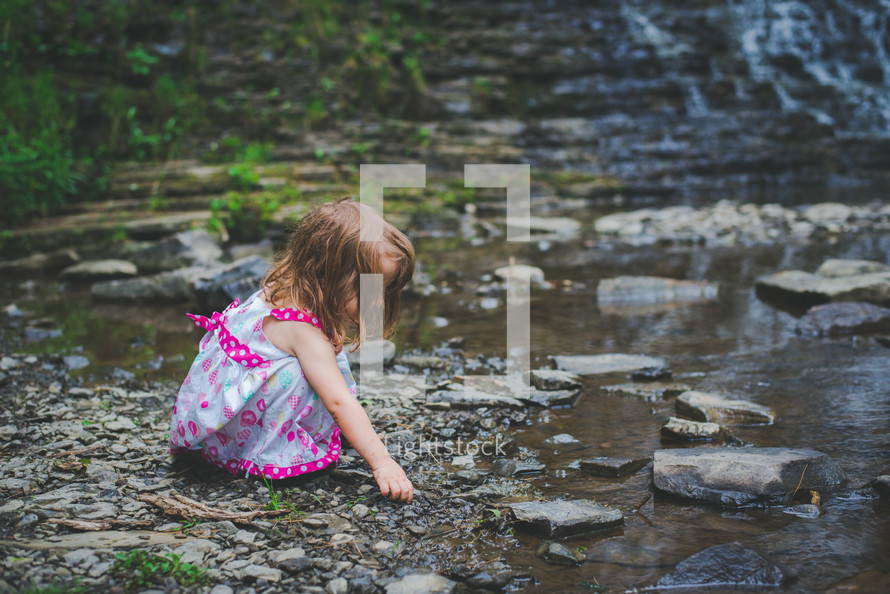a girl playing with rocks in a creek 