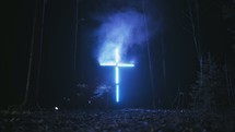cross with lights and smoke in a forest 