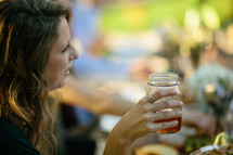 a woman drinking out of a mason jar glass 