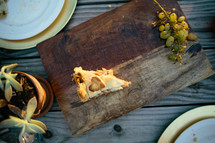 slice of pie and grapes on a wood plater 