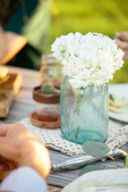 flowers in a mason jar vase on a dinner table 