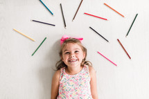 kid surrounded by colored pencils 