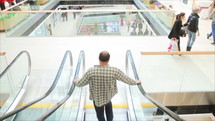 man going down an escalator in a mall 