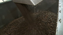 Coffee beans exiting a blender chute.