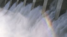 Water rushing through a hydro dam creating a rainbow in the mist.