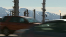Highway traffic by an oil refinery near the mountains.