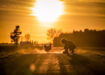 a boy and a child on a dirt road at sunset 
