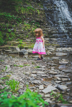 a girl playing with rocks by a stream 
