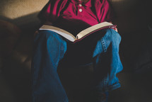  a kid reading a Bible on a couch 