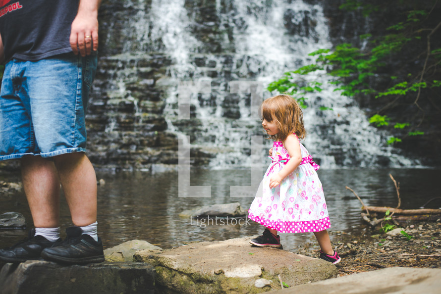 a father and daughter hiking near a creek and waterfall 
