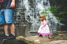 a father and daughter hiking near a creek and waterfall 