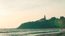 tide washing onto a shore near a lighthouse 