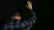 Man praying and raising his hands in worship to receive Christ.