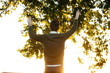man standing outdoors with raised arms 