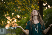 a woman with head tilted up to God standing outdoors 