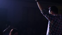a worship leader on stage with raised hand 