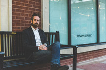 man sitting on a bench in front of a Banana Republic store 