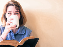 a woman drinking coffee and reading a Bible 