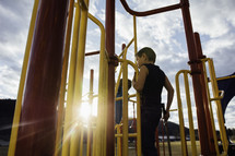 a child climbing on playground equipment with a toy sword 
