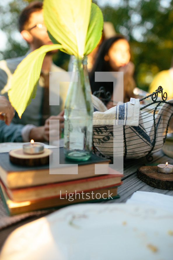 leaves in a coke bottle on top of a stack of books and a tea candle 
