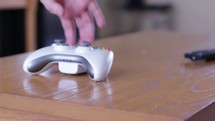 Placing a video game controller on a table and walking away. 