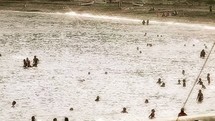 people in the water at a crowded beach 