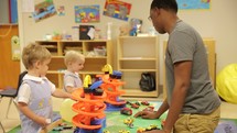 a man and toddlers in a preschool classroom